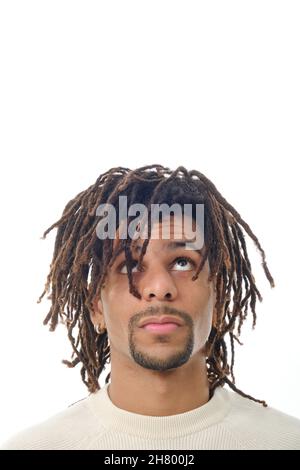Lateinischer Mann mit Dreadlocks, der vor einem isolierten Hintergrund aufschaut. Stockfoto
