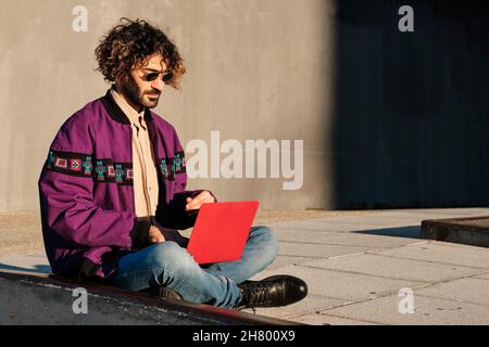 Mann mit einem Laptop, während er im Freien sitzt. Stockfoto