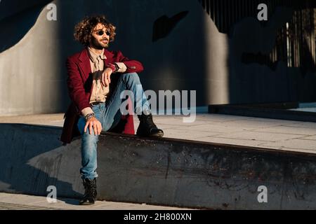 Hipster Mann gekleidet stilvoll sitzen im Freien. Stockfoto