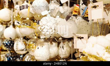 Weihnachtskugeln aus Glas und Dekorationen. Weiß mit silbernem Tannenzapfen Weihnachtsbaumschmuck aus nächster Nähe. Verkauf von Weihnachtsbaumschmuck im Chris Stockfoto