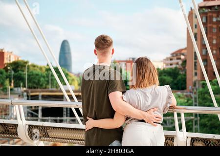 Glückliches junges Paar, ein gutaussehender Mann und ein kurvengelagertes Modell, in einer Brücke mit Blick auf die Skyline von Barcelona Stockfoto