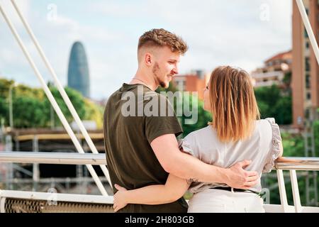 Glückliches junges Paar, ein gutaussehender Mann und ein kurvengelagertes Modell, in einer Brücke mit Blick auf die Skyline von Barcelona Stockfoto