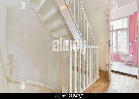 Innenraum des großen Häuschens mit Flur, der zu einer Holztreppe mit Geländer führt und eine offene Tür zum Badezimmer Stockfoto