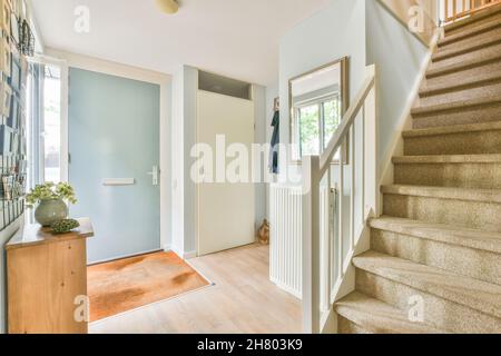 Korridor der Hütte mit Türen und Bilder hängen an der Wand über Holztisch mit Blumen in Vase und Treppe, die zum zweiten Stock in dekoriert Stockfoto