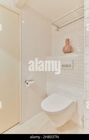 Modernes Badezimmer mit Toilettenschüssel zwischen weißen Kachelwänden im Haus Stockfoto