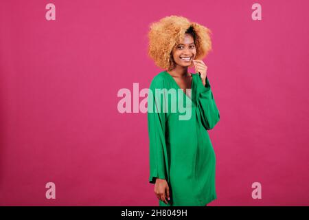 Afro-Frau, die die Kamera anschaut und lächelt, während sie sich vor einem isolierten Hintergrund posiert. Stockfoto
