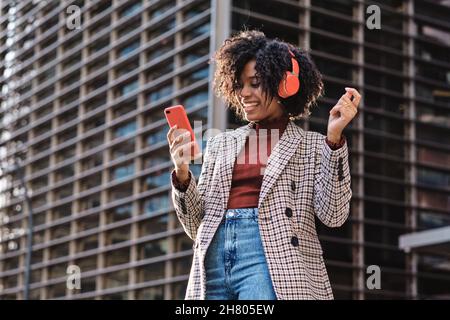 Afro Frau Musik hören und Telefon im Freien. Stockfoto