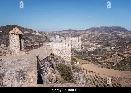 Historischer alter Steinturm über grasbewachsenen Hügeln mit grüner Vegetation vor blauem Himmel am sonnigen Sommertag in Ronda Stockfoto