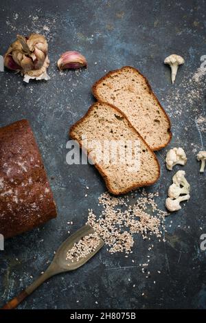 Draufsicht Aufgeschnitten von leckeren frisch gebackenen Blumenkohlebrot auf dem Tisch mit Löffel in verstreuten Sesamkörnern in der hellen Küche Stockfoto