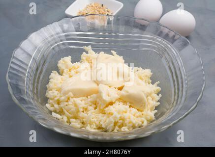 Glasschüssel mit Frischkäse und Mozzarella zum Backen kohlenhydratarmes Bagels auf dem Tisch mit Eiern in der hellen Küche Stockfoto