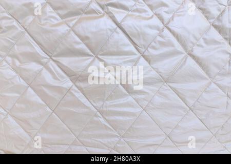 Quadratisch auf silbergrauem Mantel genäht, nahtloses Hintergrundmuster und Textur, silberner Hintergrund aus reflektierend gestepptem Stoff, Nahaufnahme Stockfoto