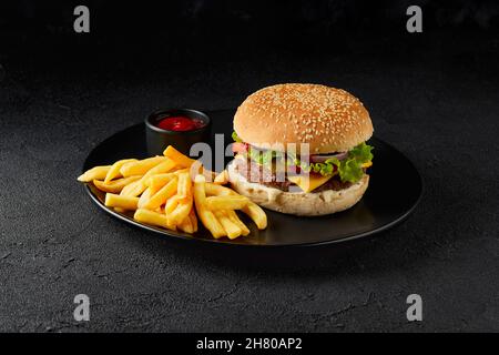 Frischer, leckerer Burger, pommes Frites und Ketchup auf dunklem Hintergrund Stockfoto