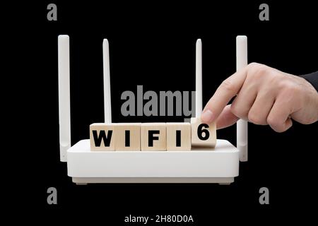 Text WIFI 6 aus Holzblöcken, die auf einem schwarzen Router stehen. Stockfoto