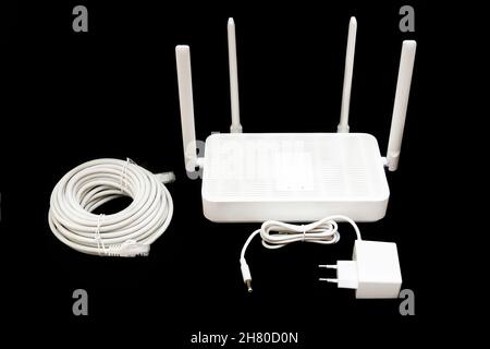 Dual-Band Wi-Fi 6 Router mit Netzteil und einer Rolle Ethernet-Kabel auf schwarz isoliert. Stockfoto