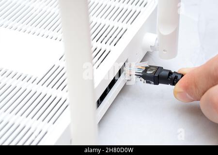 Mann, der das Internetkabel an den Router anschließt Stockfoto
