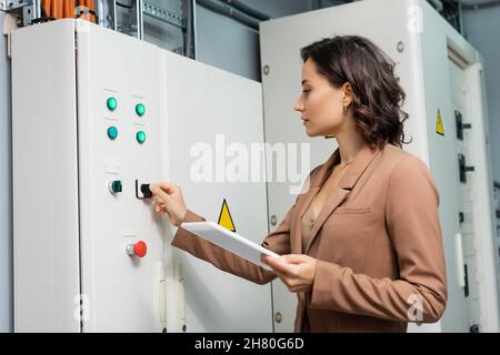 Techniker, der die Schalttafel im Rechenzentrum betreibt, während er das digitale Tablet hält Stockfoto