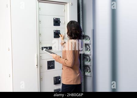 Rückansicht des Technikers mit digitaler Tablet-Bedienzentrale im Rechenzentrum Stockfoto