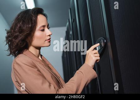 Programmierer berührt das Bedienfeld während der Diagnose des Servers im Rechenzentrum Stockfoto