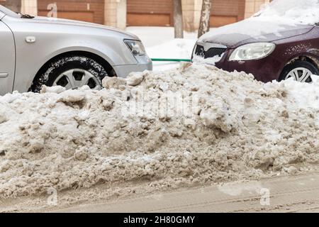 Stadtstraße Auffahrt Parkplatz mit vielen Autos von Schnee bedeckt stank nach schweren Schneesturm Schneefall am Wintertag durch schmutzige verschneite Haufen. Schneeverwehungen Stockfoto