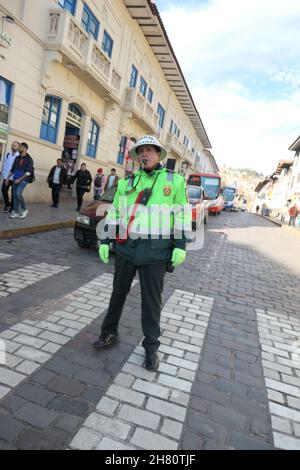 Polizist in Cuzco, Peru, Zentrum der Stadt, Verkehrspolizist mit Pfeifen, lässt Leute die Straße überqueren, Touristen überqueren, Sonnenhut-Gebläse glücklich Stockfoto