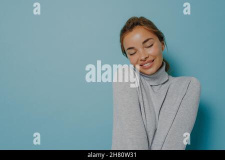 Erfreut zärtliche Frau hält die Augen geschlossen Lächeln zärtlich erinnert schönen Moment aus dem Leben Stockfoto