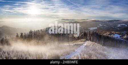 Verschneite Strecke auf dem Bergrücken, teilweise Wolken, Blick von oben auf den Wald, typische Winteratmosphäre, winterverschneite Landschaft Stockfoto