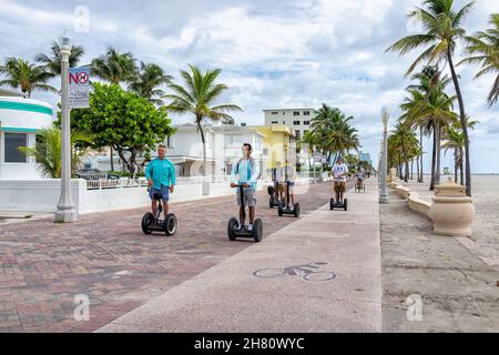 Hollywood, USA - 4. August 2021: Nördlich von Miami Beach, Hollywood Broadwalk Promenade in Florida und ehrliche Menschen auf segway Scootern erkunden wit Stockfoto