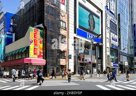 Tokio, Japan - 2. April 2019: Shinjuku-Fußgängerüberweg mit Geschäftsleuten viele Menschen haben auf dem Weg zur Kreuzung der Straße in der morgendlichen Hauptverkehrszeit auf der Straße mit Wegweisern zumute Stockfoto