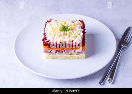 Heringsalat unter einem Pelzmantel. Traditioneller russischer, vielschichtiger Salat aus Hering, Rüben, Kartoffeln, Karotten und Eiern. Nahaufnahme, grauer Hintergrund. Stockfoto