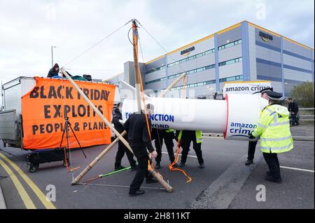 Die Polizei nimmt bei einem Aussterbeprotest eine Modellrakete ab, als sie den Eingang zum Amazon-Versandzentrum in Tilbury, Essex, blockierte und am Schwarzen Freitag, dem geschäftigsten Tag des Jahres, die ein- und Ausreise von Lastwagen verhinderte. Bilddatum: Freitag, 26. November 2021. Stockfoto