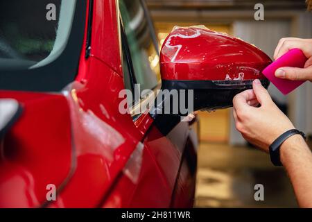 Meister Mann installiert Vinyl-Folie schützen Farbe Körper Seitenspiegel Auto. Stockfoto