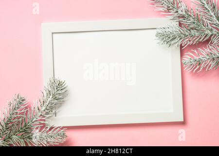 Weihnachtskomposition mit Fotorahmen und Tannenzweig auf rosa Hintergrund. Stockfoto