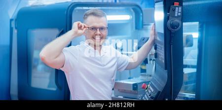 Banner Happy Industriearbeiter Mann in Gläsern, die CNC-Laser-Drehmaschine auf automatischem modernen Fabrikboden bedienen. Stockfoto