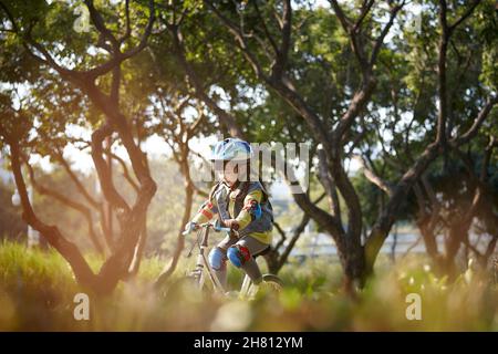 Schöne glücklich asiatische kleine Mädchen mit Helm und voller Schutz Ausrüstung Reiten Fahrrad im Stadtpark Stockfoto