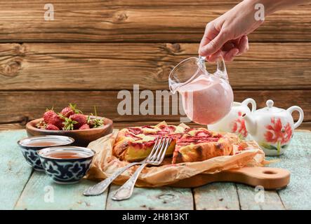 Handgegossene Sahnesauce aus dem Glas auf hausgemachten Erdbeerkuchen mit Copyspace Stockfoto