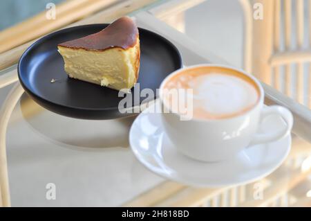 Tee oder heißer Tee oder Milchtee, thailändischer Milchtee und baskischer gebrannter Käsekuchen oder baskischer Käsekuchen auf dem Tisch Stockfoto