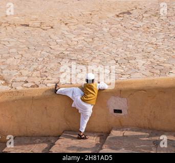 Muslimischer Junge, der versucht, eine Wand in der Nähe der Stufen zu erklimmen Stockfoto