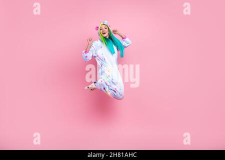 In voller Länge Körpergröße Ansicht der attraktiven fröhlichen Mädchen in kigurumi springen Jubel isoliert auf rosa Pastellfarbe Hintergrund Stockfoto