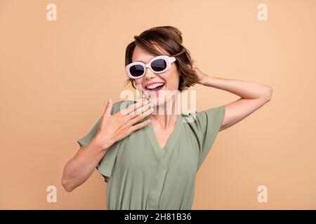 Foto von positiven glücklich erstaunt junge Frau Handgesicht tragen Sonnenglas Nachrichten isoliert auf beige Farbe Hintergrund Stockfoto