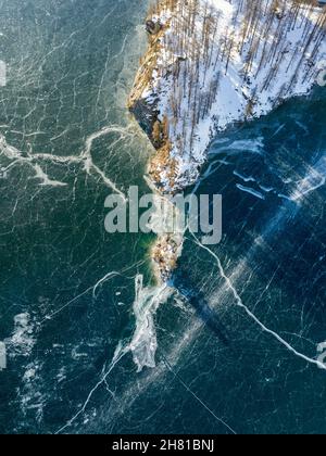 Luftaufnahme einer Inselspitze auf einem gefrorenen See mit vielen Eisrissen an der Oberfläche Stockfoto