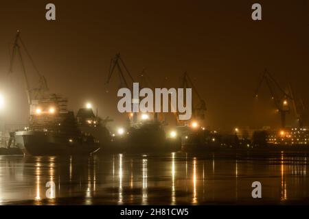 Der Bau von nuklearen Eisbrechern in der Nacht, Kräne der baltischen Werft in einem frostigen Wintertag, Dampf über dem Fluss Neva, glatte Oberfläche Stockfoto