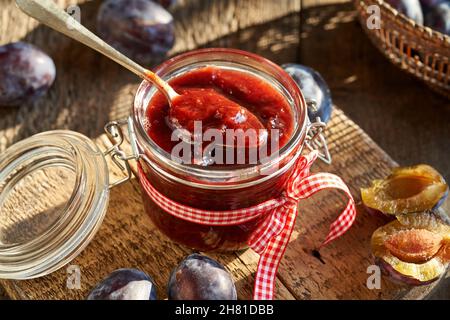 Hausgemachte Pflaumenmarmelade in einem Glasglas mit einem Löffel Stockfoto