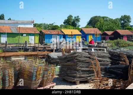 Oleron Island, Charente-Maritime, Frankreich - 7. Juni 2014: Zwei erfahrene Fischer unterhalten sich vor bunten Austernhütten im Dorfhafen Stockfoto