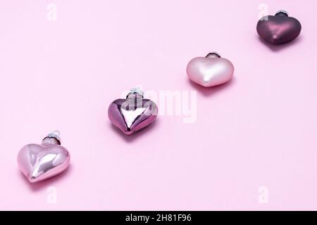 Weihnachtsschmuck in Form von Herzen aus lila und lila Blumen auf einem rosa Hintergrund. Weihnachtskarte mit Platz für Text. Stockfoto