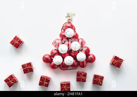 Auf weißem Hintergrund ein Weihnachtsbaum aus weißen und roten Kugeln mit einem Engel und Geschenken. Festliche Postkarte. Horizontales Foto. Stockfoto