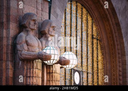 Helsinki, Finnland. Nacht Blick auf zwei Paare von Statuen, die die kugelförmige Lampen am Eingang nach Helsinki Hauptbahnhof. Am Abend oder in der Nacht Stockfoto