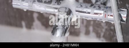 Wasserhahn aus Stahl mit Seifenschaum in der Nähe des Badezimmers Stockfoto