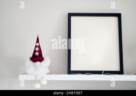 Im Innenraum steht ein leerer Bilderrahmen aus Holz auf weißem Hintergrund. Mockup Posterrahmen Nahaufnahme in der häuslichen Einrichtung. Stockfoto