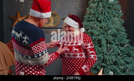 Liebevoller Großvater verschenkt Weihnachtsgeschenk Schmuckkachtel mit Goldring an überraschte Großmutter Stockfoto
