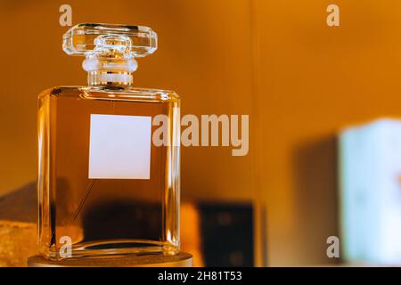 Transparente Flasche imitierte Parfüm vor goldenem Hintergrund. Lux-Flasche auf einem Ständer. Design Template für luxuriöse Parfümerie. Сopy Raum Stockfoto